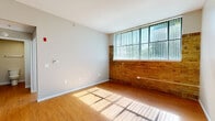 Located at 221 N Central Ave in Fairborn, Ohio, this single-floor unit offers three bedrooms, one bathroom, and a kitchen within a compact, efficiently arranged floor plan. Warm hardwood-style flooring runs consistently throughout the space, contributing to a cohesive and inviting aesthetic.

The bedrooms vary in character — the primary bedroom and an additional bedroom feature standout exposed brick accent walls paired with large windows fitted with vertical blinds, allowing generous natural light to fill the rooms while providing views of surrounding greenery. Each bedroom benefits from closet storage, with some featuring sliding or bi-fold closet doors. The neutral gray wall tones keep the rooms feeling bright and versatile.

The galley-style kitchen is lined on both sides with warm oak cabinetry offering ample storage, complemented by gray countertops, a double basin sink, and black appliances including a refrigerator and electric range with overhead ventilation.

The bathroom features a straightforward layout with a vanity with wood cabinetry, a toilet, and a shower/tub combination, all finished with the same durable hardwood-style flooring found throughout the unit.

Overall, the space presents a practical and functional design with consistent finishes, natural light, and a mix of classic brick detailing that adds character to this Fairborn residence.