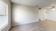 Located at 1610 E McKinney St in Denton, TX, this one-bedroom, one-bathroom unit offers a well-organized single-level layout designed for comfortable everyday living. The combined kitchen and living area serves as the heart of the home, featuring wood-look flooring throughout and a ceiling fan that adds both style and function. The kitchen is equipped with white cabinetry, a gray subway tile backsplash, laminate countertops, a stainless steel dishwasher, and a black range, providing a clean and practical cooking space. The living area offers an open, airy feel with neutral-toned walls and ample room for furnishings. The bedroom is a comfortable retreat, finished with plush wall-to-wall carpeting and a window that invites natural light. A dedicated closet provides convenient storage. The full bathroom features a soaking tub and shower combo adorned with gray subway tile surround, complemented by wood-look flooring and clean white fixtures. Throughout the unit, textured ceilings and neutral wall tones create a consistent, understated aesthetic. A hallway connects the living spaces to the private areas of the home, contributing to an efficient and functional floor plan.