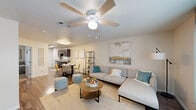 Located on Leah Ave in San Marcos, TX, this two-story home offers six bedrooms and five bathrooms spread evenly across two floors, making it well-suited for larger households. The main floor features a welcoming living room with wood-look flooring, a ceiling fan, and large windows dressed with teal curtains that fill the space with natural light. The kitchen is outfitted with rich dark wood cabinetry, light countertops, a double-basin sink, and a skylight overhead, complemented by direct access to an exterior door. A utility room and hallway round out the ground level. Upstairs, the six bedrooms are finished with soft carpeting and ceiling fans throughout. Several rooms include closets with mirrored sliding doors, and the generously sized primary bedroom connects directly to a private bathroom. The bathrooms feature wood-look tile flooring, tub-shower combinations with tile surrounds, and clean, neutral finishes. One bathroom features a uniquely angled ceiling, adding architectural character. The home's neutral color palette, consistent finishes, and practical layout provide a cohesive, comfortable living environment throughout both levels.