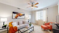 This single-floor residence offers a thoughtfully designed layout that balances comfort and functionality across its key living areas. The living room serves as the heart of the home, featuring plush wall-to-wall carpeting, crown molding, a ceiling fan with light fixture, and large windows dressed with sheer curtains and blinds that allow generous natural light to fill the space. A vibrant abstract canvas anchors the main wall, adding a bold artistic touch to the room's neutral palette. Adjacent to the living area, a dedicated dining nook provides an intimate setting for meals, accented by a round mirror that reflects light back into the space. The kitchen is outfitted with warm wood cabinetry, granite-style countertops, tile flooring, and a full suite of appliances including a stainless steel refrigerator, electric range, and built-in microwave. The bedroom is a serene retreat, complete with soft carpeting, a ceiling fan, and a bright window that fills the room with natural light. A spacious walk-in closet with multiple hanging rods and shelving offers ample storage. The bathroom features tile flooring, a tub-shower combination with full tile surround, and a granite-topped vanity, completing this comfortable and well-equipped residence.
