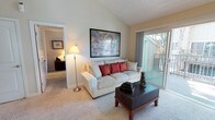 This single-floor residence offers a thoughtfully designed layout that balances comfort and functionality throughout. The entryway welcomes visitors with vaulted ceilings, warm neutral tones, and a seamless transition between hardwood-style flooring and plush carpeting.

The living room is a bright, inviting space anchored by soaring vaulted ceilings and a large sliding glass door that opens to a private balcony, flooding the room with natural light and offering pleasant outdoor views of surrounding trees. Adjacent to the living area, the dining room features a ceiling fan, a generous window framing lush greenery outside, and comfortable space for a full dining set.

The galley-style kitchen is efficiently organized with light maple cabinetry, granite-look countertops, hardwood-style flooring, and black appliances including a refrigerator, electric range, and built-in microwave — providing ample storage and prep space.

The bedroom is generously sized with plush carpeting, a large window allowing natural light, and dual sliding-door closets offering extensive storage. The bathroom features a granite-look vanity countertop and warm, neutral finishes that carry throughout the home.

Overall, the residence presents a cohesive, warm aesthetic with consistent neutral tones, vaulted ceilings in key living areas, and abundant natural light that creates an airy and welcoming ambiance.