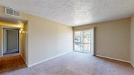 This single-floor unit offers four bedrooms and two bathrooms across a well-organized layout designed to maximize functionality. The combined kitchen and living room serves as the heart of the home, with the kitchen featuring light wood cabinetry, granite-style laminate countertops, a double-basin sink, and durable hardwood-style flooring. The living room is carpeted and bathed in natural light, highlighted by a sliding glass door that opens to a private balcony overlooking a lush outdoor setting — a standout feature of the space.

Each of the four bedrooms is finished with neutral-toned carpet and features closets with bifold doors, providing practical storage. The primary bedroom is generously sized and includes a ceiling fan, adding to the room's comfort. The remaining bedrooms are well-proportioned, with clean walls and textured ceilings consistent throughout the unit.

The two bathrooms are finished with hardwood-style flooring, warm wood vanity cabinetry, and granite-style countertops. A hallway connects the rooms and includes additional closet space. The unit's warm beige color palette, textured ceilings, and consistent finishes throughout create a cohesive and comfortable living environment suited for everyday use.