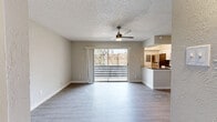 This single-story, one-bedroom, one-bathroom unit offers an efficient and thoughtfully designed layout across a comfortable footprint. The open-concept living and kitchen area serves as the heart of the home, showcasing light-toned luxury vinyl plank flooring, a textured ceiling, and a ceiling fan that enhances airflow throughout. A standout wood-burning fireplace with a clean white surround anchors one wall of the living room, adding warmth and character. Sliding glass doors flood the space with natural light and provide direct access to a private outdoor patio enclosed by a horizontal wood fence, offering a sense of privacy and a glimpse of mature trees beyond.

The kitchen features a peninsula counter with dark countertops, white cabinetry, subway tile backsplash, a stainless steel refrigerator, and track lighting overhead — seamlessly connecting to the living area for an open, social feel.

The bedroom is a well-proportioned retreat with its own ceiling fan, a window with natural light, and the same consistent vinyl plank flooring. A dedicated closet provides organized storage. The bathroom includes a full tub and shower combination with a modern rain-style showerhead. A hallway connects the spaces cleanly, completing this cohesive and move-in-ready layout.