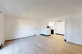 Located at 1211 South Quebec Way in Denver, Colorado, this two-bedroom, one-bathroom residence offers a practical and well-organized single-floor layout. The open living room features light wood-style flooring, a textured ceiling, baseboard heating, and a sliding glass door that leads to a private balcony, bringing in natural light and outdoor views. An in-wall AC unit adds comfort to the space.

The galley-style kitchen has been thoughtfully updated with crisp white cabinetry, marble-look countertops, and light wood flooring. Black appliances, including a refrigerator, electric range, and dishwasher, provide a modern contrast against the clean white finishes.

Both bedrooms are carpeted and feature textured ceilings, baseboard heating, and windows with blinds that let in natural light. The primary bedroom offers generous closet space with wide bifold louvered doors, while the second bedroom includes a ceiling fan and additional closet storage.

The bathroom is clean and functional, featuring a full soaking tub with shower, white tile surround, and a vanity with a marble-look countertop — consistent with the updated finishes found throughout the home. Light wood flooring ties the bathroom together with the rest of the residence.