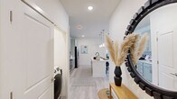 Located at 210 Brunswick Pl in Myrtle Beach, SC, this well-appointed single-floor home offers two bedrooms and two bathrooms with a clean, modern aesthetic throughout. The open-concept kitchen and living area serves as the heart of the home, where sage-green shaker cabinets, a classic subway tile backsplash, white quartz countertops, and stainless steel appliances create a polished, functional space. A center island with seating for three anchors the kitchen, illuminated by elegant pendant lighting. The adjoining living room is bright and welcoming, with multiple windows allowing generous natural light, light wood-look flooring, and direct access to an outdoor area. The primary bedroom features plush carpet, a ceiling fan, natural light from large windows, and a dedicated closet with an en-suite bathroom showcasing a glass-enclosed walk-in shower with white subway tile and brushed gold fixtures. The second bedroom mirrors the same comfort and style. The second bathroom offers a full tub-shower combination with sage cabinetry and a framed vanity mirror. Throughout the home, a neutral warm palette, light flooring, and thoughtful details create a cohesive, inviting atmosphere ideal for modern living.