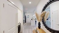 Located at 210 Brunswick Pl in Myrtle Beach, SC, this well-appointed single-floor home offers two bedrooms and two bathrooms with a clean, modern aesthetic throughout. The open-concept kitchen and living area serves as the heart of the home, where sage-green shaker cabinets, a classic subway tile backsplash, white quartz countertops, and stainless steel appliances create a polished, functional space. A center island with seating for three anchors the kitchen, illuminated by elegant pendant lighting. The adjoining living room is bright and welcoming, with multiple windows allowing generous natural light, light wood-look flooring, and direct access to an outdoor area. The primary bedroom features plush carpet, a ceiling fan, natural light from large windows, and a dedicated closet with an en-suite bathroom showcasing a glass-enclosed walk-in shower with white subway tile and brushed gold fixtures. The second bedroom mirrors the same comfort and style. The second bathroom offers a full tub-shower combination with sage cabinetry and a framed vanity mirror. Throughout the home, a neutral warm palette, light flooring, and thoughtful details create a cohesive, inviting atmosphere ideal for modern living.