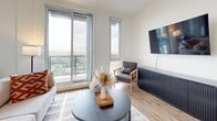 Located at 140 Ferguson Dr in Woodstock, Ontario, this thoughtfully designed one-bedroom unit offers a well-appointed single-floor layout with modern finishes and a bright, contemporary aesthetic throughout.

The open-concept kitchen and living area forms the heart of the unit. The kitchen features dark flat-panel cabinetry with under-cabinet lighting, white subway tile backsplash, white quartz countertops, and stainless steel appliances including a built-in microwave, electric range, and dishwasher. A built-in desk nook with open shelving sits adjacent to the kitchen, offering a functional workspace.

The living area is filled with natural light from floor-to-ceiling sliding glass doors and tall vertical windows that open to a private balcony, offering open views of the surrounding Woodstock neighbourhood. Light wide-plank hardwood flooring flows seamlessly throughout the entire unit.

The bedroom is a well-proportioned retreat featuring clean white walls, warm accent lighting, and a sliding door that connects directly to a stylish ensuite bathroom. The ensuite is finished with dark navy cabinetry and open shelving, providing practical storage with a designer touch.

Overall, the unit presents a clean, modern ambiance with a cohesive dark-and-light design palette, making it an efficient and stylish living space.