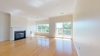 This single-floor residence is designed with a clean, open layout that maximizes both space and natural light throughout. The living room serves as the centerpiece of the home, featuring warm hardwood flooring, elegant crown molding, and a fireplace framed by classic white millwork. Large windows and a sliding glass door flood the room with sunlight while providing direct access to a private balcony overlooking lush tree-lined views. The adjoining kitchen is efficiently designed with warm honey-toned cabinetry, granite countertops, and a full suite of stainless steel appliances including a gas range, microwave, and refrigerator. Tile flooring and a peninsula counter add both function and definition to the space. A wide hallway connects the living areas to the private quarters, offering additional closet storage along the way. The bedrooms are carpeted for comfort, bathed in natural light, and include generous walk-in closets with built-in shelving. Two bathrooms serve the home; one features a single white vanity with ample storage, while the other offers a dual-sink setup with rich wood cabinetry, wide mirrors, and tile flooring. The overall aesthetic is bright, neutral, and move-in ready.