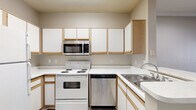 Located at 2440 North Blvd in Houston's 77098 zip code, this one-bedroom, one-bathroom unit at The Boulevard offers a well-organized single-floor layout. The kitchen is efficiently designed in an L-shape configuration, featuring white cabinetry with oak-trimmed accents, light countertops, and a full suite of appliances including an electric range, over-the-range microwave, stainless steel dishwasher, and refrigerator. Wood-look vinyl flooring runs through the kitchen, lending a clean, modern feel. The living area transitions into a comfortable, neutral-toned space with wood-style flooring that adds warmth throughout the main areas. The bedroom is carpeted for comfort and is brightened by a large grid-pane window that invites natural light and outdoor views. A ceiling fan provides additional airflow. The bathroom is neatly appointed with wood-trimmed vanity cabinetry, a white countertop with an undermount sink, a mirrored medicine cabinet, and a tiled tub and shower combination. Wood-look vinyl flooring continues in the bathroom, tying the unit together cohesively. Overall, the unit presents a functional and tidy living environment with a neutral color palette throughout.