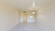 Located in Miami, FL, this one-bedroom, one-bathroom unit offers a clean, light-filled layout spread across a single floor. White large-format ceramic tile flooring runs consistently throughout the entire space, lending a cohesive and airy feel.

The living and dining areas are generously proportioned, benefiting from two large windows dressed with vertical blinds that allow abundant natural light and outdoor views of surrounding greenery. A pendant light fixture anchors the dining zone, adding a subtle decorative touch.

The galley-style kitchen is efficiently designed with white cabinetry — both upper and lower — light-toned countertops, a stainless steel sink, electric range, and a full-size refrigerator. A pass-through window connects the kitchen to the living area, enhancing the sense of openness.

The bedroom is a comfortable, well-lit retreat with a wide window providing natural light and outdoor views, along with access to dedicated closet space. The unit features a notably generous total of four closets, providing exceptional storage throughout.

The bathroom is bright and cleanly finished, featuring an open walk-in shower with classic mosaic tile flooring, a toilet, and a vanity. A window with blinds allows natural ventilation while maintaining privacy. A hallway connects all rooms, keeping the floor plan organized and functional.