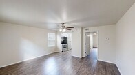 Located at 1900 NW A St in Bentonville, Arkansas, this single-floor, one-bedroom, one-bathroom residence offers a thoughtfully laid-out living space with a clean, modern aesthetic. Rich wood-style flooring runs throughout the entire unit, providing a cohesive and warm feel from room to room.

The open living area is bright and welcoming, featuring a ceiling fan with light fixture and a window dressed with blinds that allows natural light to fill the space. The galley-style kitchen is well-equipped with stainless steel appliances — including an electric range, microwave, and refrigerator — complemented by crisp white cabinetry with black hardware, a double-basin sink with a brushed nickel faucet, and light countertops.

A hallway connects the main living area to the private bedroom, which is generously proportioned and includes its own ceiling fan, a window with natural light, and access to closet space. Two closets provide ample storage throughout the unit. The full bathroom features a white vanity with integrated sink, a tub/shower combo, and continues the wood-style flooring seen throughout the home.

A dedicated in-unit laundry area with full-size washer and dryer hookups adds everyday convenience. The space is finished with neutral tones and white trim throughout, creating a clean and move-in ready environment.