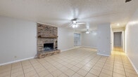 This single-story home offers a practical and comfortable layout across several well-defined living spaces. The main living area serves as the focal point of the home, anchored by a full-height brick fireplace with a wood mantel that adds warmth and character. Light-colored ceramic tile flooring extends throughout the common areas, and two ceiling fans provide air circulation overhead. A textured popcorn ceiling is consistent throughout the main areas. The living space flows openly into an adjoining room, which benefits from a large window that draws in natural light and offers a view of the surrounding landscape.

The kitchen features white cabinetry, laminate countertops, a textured tile backsplash, and white appliances including a refrigerator, dishwasher, and a double-basin sink. A dedicated laundry area accommodates a full-sized washer and includes overhead cabinet storage.

The bedrooms are carpeted for comfort, each equipped with a ceiling fan and natural light from windows fitted with blinds. At least one bedroom includes a reach-in closet with shelving and hanging rods. The bathroom is finished with tile flooring, a white vanity with drawers, and a full tub-shower combination. Neutral tones throughout create a clean, move-in-ready atmosphere.