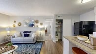 Located at 3200 Hartley Rd in Jacksonville, FL, this well-designed one-bedroom, one-bathroom residence offers a thoughtful single-floor layout that maximizes every square foot. The open-concept living area flows seamlessly between two distinct living spaces, both finished with warm hardwood-style flooring. Large windows dressed with patterned curtains invite abundant natural light throughout, creating a bright and welcoming ambiance. The neutral gray walls serve as a versatile backdrop, complemented by textured ceilings throughout the unit.

The kitchen is well-appointed with white cabinetry, granite-style countertops, a mosaic tile backsplash, and black appliances including a refrigerator and electric range. A peninsula counter connects the kitchen to the living area, enhancing the open feel and providing additional prep space.

The bedroom is generously sized, featuring plush carpeting, large windows that allow ample natural light, and a dedicated closet with open shelving for organized storage. The full bathroom is clean and functional, complete with a tiled shower-tub combination, a white vanity, and wood-style flooring. The overall design is cohesive and move-in ready, making this a practical and comfortable residence in Jacksonville's 32257 corridor.