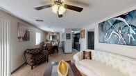 This single-floor residence offers a thoughtfully designed layout that balances comfort and functionality throughout. The open-concept living and dining area serves as the heart of the home, featuring plush carpeting, a ceiling fan with light fixture, and a sliding glass door that fills the space with natural light. The living room is generously proportioned, accommodating multiple seating areas alongside a substantial wood-and-glass coffee table and vibrant wall art. The adjacent dining area includes a classic mirror-accented wall, adding depth and elegance to the space.

The kitchen is outfitted with dark cabinetry, stainless steel appliances, and striking granite countertops, providing ample workspace and storage. Tile flooring runs throughout this area for easy maintenance.

The primary bedroom is a serene retreat with carpet flooring, rich dark-wood furniture, and a window that brings in soft natural light. It connects directly to a private en-suite bathroom featuring tile flooring, a tub-shower combination with decorative tile accents, and a granite-topped vanity.

Two additional bedrooms offer comfortable, carpeted spaces with natural light from windows, suitable for a variety of uses. A shared full bathroom with a tiled tub-shower serves these rooms. Throughout, textured ceilings and neutral tones create a cohesive and inviting atmosphere.