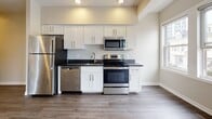 Located on Atwells Avenue in Providence, Rhode Island, this single-floor unit offers a thoughtfully designed layout with modern finishes throughout. The open-concept living area is bathed in natural light, courtesy of multiple double-hung windows that frame views of the surrounding neighborhood. Durable hardwood-style flooring flows across the main living spaces, complementing the neutral, warm-toned walls that create a clean and welcoming atmosphere. The kitchen is well-appointed with white shaker-style cabinetry, dark granite countertops, and a full suite of stainless steel appliances, including a refrigerator, range, microwave, and dishwasher — offering both style and practicality. A dedicated bedroom features plush carpeting and generous window placement, allowing ample natural light and neighborhood views. The bathroom is finished with modern tile flooring, a sleek floating vanity with a white countertop, a glass-enclosed shower, and a window for natural ventilation. Additional living or flex spaces continue the hardwood-style flooring with recessed lighting accents. The overall design presents a cohesive, contemporary aesthetic with a neutral palette, making this a versatile and move-in ready space in the heart of Providence.