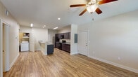 This single-story unit in Foley, Alabama offers a thoughtfully designed layout that maximizes functionality across its one-bedroom, one-bathroom floor plan. Wood-look plank flooring runs consistently throughout, lending a cohesive, clean aesthetic to every room.

The open-concept living and kitchen area forms the heart of the unit. Vaulted ceilings with a ceiling fan add a sense of vertical spaciousness to the living area, which receives natural light through windows and a private exterior door. The kitchen is well-equipped, featuring dark espresso cabinetry, granite countertops, a double undermount sink, and black appliances including an electric range, built-in microwave, and stainless steel refrigerator. A peninsula with additional counter space provides a natural division between the kitchen and living area.

The bedroom is generously sized with a ceiling fan, natural light from multiple windows, and an exterior door. Neutral wall tones complement the warm flooring throughout.

The bathroom includes a tub-shower combination with built-in shelving, a toilet, and an adjacent walk-in closet with wire shelving. Recessed lighting and wood-look flooring complete the space. An electrical panel is conveniently accessible within the unit.