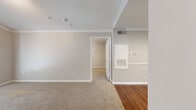 Located at 8300 Canyon St in Houston, TX, this single-story, one-bedroom, one-bathroom home offers a well-organized layout across a compact yet functional floor plan. The living area makes a strong impression with vaulted ceilings accented by crown molding, track lighting, and a set of French doors that invite natural light and provide access to the outdoors. Neutral carpet and soft gray walls create a calm, versatile atmosphere throughout. The kitchen is efficiently designed with granite-look countertops, a breakfast bar pass-through, white upper cabinetry, black appliances including a refrigerator and range, and rich hardwood-style flooring. Built-in open shelving adds practical storage near the kitchen entry. The bedroom is a comfortable, carpeted retreat featuring a ceiling fan and a window with views of surrounding greenery. It connects conveniently to a walk-in closet outfitted with wire shelving along multiple walls, offering generous storage capacity. The bathroom includes a full soaking tub with tile surround, accessible from the hallway. Hardwood-style flooring extends through the hallway and main areas, tying the space together with a warm, cohesive feel throughout.