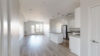 Located at 71 Connecticut Ave in Norwalk, CT, this well-designed 2-bedroom, 2-bathroom residence offers a clean, modern aesthetic across its single-floor layout. The open-concept living and kitchen area serves as the heart of the home, featuring light wood-style flooring that flows seamlessly throughout the space. The kitchen is outfitted with crisp white shaker cabinetry, granite countertops, a central island with pendant lighting, and a full suite of stainless steel appliances including a refrigerator, electric range, microwave, and dishwasher. A track lighting system and recessed lighting add to the bright, airy atmosphere. The living area extends toward a glass door that opens to a private balcony, allowing natural light to fill the space. Both bedrooms are comfortably sized with large windows offering neighborhood views and ample natural light. The primary bedroom provides a practical and well-proportioned retreat. Each of the two bathrooms features a white vanity with under-cabinet storage, a large mirror, tub-shower combination, and wood-tone flooring, maintaining a consistent modern finish. The overall design is characterized by a neutral palette, clean lines, and contemporary hardware throughout.