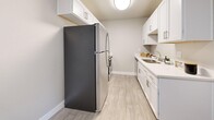 Located in Millcreek, Utah, this 2-bedroom, 2-bathroom residence offers a well-organized single-level layout designed for comfortable everyday living. The living room is bright and open, featuring light hardwood-style flooring, a ceiling fan, and sliding glass doors with vertical blinds that lead to a private balcony, filling the space with natural light. The galley-style kitchen is thoughtfully updated with white shaker cabinetry, sleek hardware, light quartz countertops, a stainless steel sink, and stainless steel appliances including a full-size refrigerator. Both bedrooms are carpeted and serene, each featuring a closet with sliding doors. The primary bedroom offers a comfortable, well-proportioned retreat. The two bathrooms are clean and modern, with one showcasing a white vanity, quartz countertop, and large mirror, while the other includes a shower with a curtain and hardwood-style flooring throughout. A dedicated laundry room houses a full-size washer and dryer alongside the water heater, adding everyday convenience. Neutral tones, baseboard heating, and a consistent design palette create a cohesive and move-in-ready ambiance throughout the home.