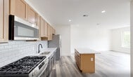 Located at 448 S Orange Ave in Newark, NJ, this thoughtfully designed two-bedroom, one-bathroom residence offers a clean, contemporary aesthetic throughout its well-appointed single floor. Light wood-tone flooring flows seamlessly across all living areas, complementing the bright white walls and recessed lighting that create an airy, welcoming atmosphere.

The open-concept kitchen is a standout feature, showcasing two-toned cabinetry with warm natural wood uppers and charcoal lower cabinets, white quartz countertops, a classic subway tile backsplash, and stainless steel appliances including a gas range, built-in microwave, and dishwasher. A central kitchen island with a matching quartz surface provides additional prep and storage space.

Both bedrooms are well-proportioned and bathed in natural light through large windows that frame outdoor views of the surrounding neighborhood. The spacious primary bedroom offers a comfortable, versatile layout. A dedicated closet adds convenient storage.

The bathroom is finished to a high standard, featuring large-format marble-look wall tiles, a soaking tub with a full tile surround, a sleek white floating vanity, and matte black fixtures and hardware throughout, delivering a modern, cohesive look.