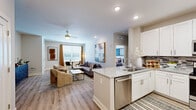Located at 2300 Swift St in North Kansas City, MO, this thoughtfully designed one-bedroom, one-bathroom residence offers a comfortable and functional single-floor layout. The open-concept living and kitchen area creates a seamless flow, anchored by wood-style plank flooring and recessed lighting throughout. The kitchen is a standout feature, boasting crisp white shaker cabinetry, granite countertops, a mosaic tile backsplash, a peninsula with an undermount sink, and a full suite of stainless steel appliances including a refrigerator, range, microwave, and dishwasher. The living area is bright and welcoming, with large windows that invite natural light and a ceiling fan overhead. The entry foyer provides a gracious welcome with ample wall space and direct access to the main living areas. The bedroom is a serene retreat, finished with plush carpet, a ceiling fan, and a generous window. It connects to a dedicated walk-in closet with wire shelving for organized storage. The bathroom features white cabinetry, dual sinks, and granite countertops, echoing the refined finishes found throughout the home. Neutral tones and clean lines give the entire space a modern, move-in-ready appeal.