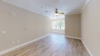 Located in Summerville, SC, this single-story, 3-bedroom, 2-bathroom home offers a well-designed layout with comfortable, functional living spaces throughout. The open-concept living room and kitchen area serves as the heart of the home, featuring light wood-look tile flooring, neutral warm-toned walls, a ceiling fan with light fixture, and a large window that fills the space with natural light. The kitchen is outfitted with rich dark cabinetry, white countertops, a subway tile backsplash, stainless steel refrigerator, and additional appliances, complemented by a convenient pantry closet. Both bathrooms mirror each other in style, showcasing dark vanity cabinetry, white countertops, wood-look tile flooring, and brushed nickel hardware. One bathroom includes a shower/tub combination. The bedrooms feature plush carpet flooring, ceiling fans, and windows that invite natural light and outdoor views. A dedicated laundry room houses a full-size washer and dryer with wire shelving above for added storage. The attached garage provides additional utility space with built-in overhead lighting and a standard garage door. Clean finishes, consistent neutral tones, and thoughtful details make this a move-in ready home.