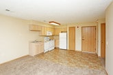 This single-floor unit offers a straightforward, functional layout designed for comfortable everyday living. The open-concept living and kitchen area combines neutral-toned walls with a transition between tile-style flooring in the kitchen zone and plush carpeting in the living space. The kitchen is well-equipped with light wood cabinetry offering generous upper and lower storage, a double-basin sink, white appliances including a range, microwave, and refrigerator, and overhead flush lighting. A dedicated pantry door provides additional storage convenience.

The living area is spacious and open, with a textured ceiling and a large window that allows natural light to fill the room. The unit includes multiple bedrooms, each finished with wall-to-wall carpet, ceiling fans with integrated lighting, and wood-toned doors. The primary bedroom is notably well-appointed, featuring two closets with built-in shelving and a built-in dresser, along with a window overlooking the exterior. A secondary bedroom also features carpet and a bright window.

The unit includes two bathrooms. The first features a walk-in shower with grab bars and tile-style flooring, while the second offers a full tub-shower combination. Both bathrooms include a toilet, vanity, and chrome hardware accents, maintaining a clean and cohesive aesthetic throughout the unit.