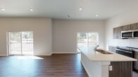 This thoughtfully designed one-bedroom, one-bathroom residence in Memphis, TN offers a clean, modern aesthetic throughout its single-story layout. Rich wood-look flooring flows consistently across all living areas, anchoring the bright, neutral interior palette. The open-concept living and dining area is filled with natural light from a sliding glass door that leads to a private balcony, offering pleasant outdoor views. Ceiling fans with integrated lighting are featured in both the living area and bedroom, enhancing comfort and airflow. The kitchen is well-appointed with warm wood-toned cabinetry, white subway tile backsplash, quartz countertops, a peninsula with an undermount sink, and a full suite of stainless steel appliances including a refrigerator, electric range, and built-in microwave. The bedroom features a spacious walk-in closet, a ceiling fan, and a window that brings in ample natural light. The bathroom is finished with marble-look tile flooring, a walk-in shower with large-format marble-style tile walls and hexagonal mosaic floor tile, a quartz-topped vanity with wood cabinetry, and modern fixtures. A wide entry hallway with high ceilings provides a welcoming transition into the main living spaces, completing this refined and functional home.