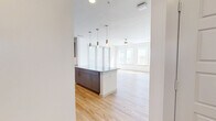 This thoughtfully laid-out 2-bedroom, 2-bathroom residence offers a clean, contemporary aesthetic throughout its single floor. The open-concept kitchen and living area serves as the heart of the home, featuring light hardwood flooring, a large granite-topped island with pendant lighting, and a full suite of stainless steel appliances. The kitchen is outfitted with two-tone cabinetry — warm taupe uppers paired with grey lowers — and a classic subway tile backsplash, delivering both style and functionality. A bank of large windows floods the living area with abundant natural light, enhanced by a ceiling fan overhead.

Both bedrooms are carpeted and offer a quiet, comfortable retreat. The primary bedroom includes direct access to a dedicated bathroom and a walk-in closet. The en-suite primary bathroom features a double-sink granite vanity with grey cabinetry, wood-look flooring, and a separate water closet. The second bathroom is equally well-appointed, with a granite vanity, a tiled soaking tub and shower combination, and coordinating finishes. Additional highlights include a dedicated laundry room, a hallway connecting the private spaces, and consistent use of neutral tones and quality materials throughout the residence.