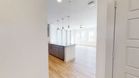 This thoughtfully laid-out 2-bedroom, 2-bathroom residence offers a clean, contemporary aesthetic throughout its single floor. The open-concept kitchen and living area serves as the heart of the home, featuring light hardwood flooring, a large granite-topped island with pendant lighting, and a full suite of stainless steel appliances. The kitchen is outfitted with two-tone cabinetry — warm taupe uppers paired with grey lowers — and a classic subway tile backsplash, delivering both style and functionality. A bank of large windows floods the living area with abundant natural light, enhanced by a ceiling fan overhead.

Both bedrooms are carpeted and offer a quiet, comfortable retreat. The primary bedroom includes direct access to a dedicated bathroom and a walk-in closet. The en-suite primary bathroom features a double-sink granite vanity with grey cabinetry, wood-look flooring, and a separate water closet. The second bathroom is equally well-appointed, with a granite vanity, a tiled soaking tub and shower combination, and coordinating finishes. Additional highlights include a dedicated laundry room, a hallway connecting the private spaces, and consistent use of neutral tones and quality materials throughout the residence.