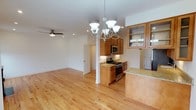 This thoughtfully designed 3-floor residence offers a seamless blend of functionality and style. The open-concept main living area is anchored by gleaming light hardwood floors that extend throughout, creating a warm and cohesive atmosphere. The kitchen is a standout feature, showcasing rich warm-toned wood cabinetry, light granite countertops, and a full suite of stainless steel appliances including a gas range and built-in microwave. A peninsula with a breakfast bar provides additional prep space and casual seating, while glass-front upper cabinets add a refined touch. An elegant chandelier with a classic multi-arm design hangs above the kitchen area, complementing the recessed lighting that illuminates the open living space beyond. A ceiling fan in the adjacent living area ensures year-round comfort. The clean white walls and bright, airy feel of the main floor lend the space a welcoming and move-in-ready quality. With three floors of living space, this residence offers ample room for both everyday living and entertaining, with a well-considered layout that balances open communal areas with the privacy afforded by multiple levels.