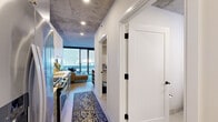 Located in Chicago's vibrant River North neighborhood, this one-bedroom, one-bathroom residence offers a thoughtfully designed layout across a single floor. The space is defined by its striking exposed concrete ceilings, which lend an industrial-chic character throughout, complemented by light hardwood-style flooring and crisp white walls.

The open-concept kitchen and living area forms the heart of the home. The kitchen is outfitted with stainless steel appliances, a gas range, grey shaker-style cabinetry with gold hardware, white upper cabinets, a herringbone tile backsplash, and ample counter space. The living area flows naturally from the kitchen and leads to floor-to-ceiling sliding glass doors that open to a private balcony, filling the space with natural light and offering urban views of the Chicago skyline.

The bedroom features the same exposed concrete ceiling, creating a cohesive industrial aesthetic, with direct access to the bathroom. The bathroom is well-appointed with a grey vanity, white quartz countertop, subway tile tub surround, and matte black fixtures with gold hardware accents. A dedicated laundry area includes a stacked full-size washer and dryer alongside built-in shelving for added storage. The entrance hallway connects all rooms efficiently, maximizing the use of every square foot.