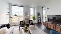 This single-floor residence showcases a contemporary design with clean lines, neutral tones, and dark hardwood flooring throughout. The living area is bright and open, featuring floor-to-ceiling windows that frame sweeping city views and connect to a private balcony furnished for outdoor relaxation. The space is anchored by a low-profile sofa, modern accent lighting, and bold wall art.

The kitchen is outfitted with stainless steel appliances, including a gas range and large refrigerator, complemented by light wood and white cabinetry, a tile backsplash, and a white quartz countertop with an integrated sink.

Multiple bedrooms offer a calm, minimalist aesthetic. The primary bedroom includes direct balcony access through sliding glass doors, a built-in closet, and city views. Additional bedrooms feature large windows with city vistas and ample storage.

Two bathrooms serve the residence: one with a glass-enclosed walk-in shower with large-format tile and a wood-accented vanity, and a second with a soaking tub, shower combination, and light tile finishes. Together, the rooms create a cohesive, sophisticated living environment with abundant natural light and elevated urban views.