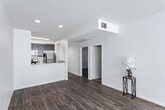 Located at 920 Wilcox Ave in the vibrant Hollywood neighborhood of Los Angeles, this single-floor residence offers a clean, modern aesthetic throughout. Rich wood-style flooring runs seamlessly across the living areas and bedrooms, providing a warm and cohesive feel. The spacious living room is a standout feature, anchored by a sleek fireplace with tile surround and a large window dressed with vertical blinds that invites an abundance of natural light. The open-concept kitchen is well-equipped with dark espresso cabinetry, white countertops, a stainless steel double sink, and stainless steel appliances including a gas range and over-the-range microwave. A structural column subtly defines the transition between the kitchen and living areas. The bedrooms are generously proportioned, each featuring wood-style flooring, large windows for natural light, and access to closet space. The bathrooms are finished with dark vanity cabinetry, white countertops, tile flooring, and glass-enclosed tub-shower combinations, maintaining a consistent modern design language. Recessed lighting and clean white walls throughout lend the home a bright, airy ambiance well-suited to the Southern California lifestyle.