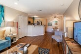 Located at 1700 S Araby Dr in Palm Springs, CA, this single-story residence offers a well-designed layout that balances comfort and functionality. Rich hardwood flooring flows throughout the main living areas, creating a warm and cohesive aesthetic.

The living room serves as the heart of the home, featuring recessed lighting, a large sliding glass door with vertical blinds that invite natural light and provide access to the outdoor area. A bold teal abstract artwork anchors one wall, complementing the eclectic furnishings that include a woven coffee table, colorful media console, and patterned area rug.

The kitchen is well-appointed with light wood cabinetry, granite countertops with a breakfast bar, stainless steel appliances including a gas range and refrigerator, and a window that keeps the space bright and airy.

The bedroom offers a calm retreat with plush carpet flooring, a generously sized window overlooking lush outdoor greenery, and warm ambient lighting. The bathroom is clean and functional, featuring a full tub and shower combination with wood-toned flooring that ties into the home's overall design palette.

Throughout the residence, neutral wall tones and consistent finishes create a cohesive, inviting atmosphere well-suited to the sunny Palm Springs lifestyle.