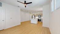 Located in Boerne, TX, this well-designed 2-bedroom, 2-bathroom residence offers a thoughtful single-floor layout with modern finishes throughout. The open-concept living and kitchen area serves as the heart of the home, featuring light wood-tone flooring, recessed lighting, and a ceiling fan. The kitchen is outfitted with taupe flat-front cabinetry, stainless steel appliances including a refrigerator, range, and microwave, white subway tile backsplash, light quartz countertops, and a central island with pendant lighting — ideal for both cooking and casual dining. A bright hallway connects the main living area to the private quarters. Both bedrooms are carpeted and receive natural light through large windows fitted with blinds. The primary bedroom includes multiple windows and a ceiling fan, while a walk-in closet with built-in shelving provides generous storage. The bathrooms feature wood-tone flooring, white shaker-style vanities with wide mirrors, and a tub-shower combination. Additional spaces include a dedicated laundry area, utility room, and multiple closets, rounding out a functional and clean living environment.