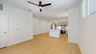 Located in Boerne, TX, this well-designed 2-bedroom, 2-bathroom residence offers a thoughtful single-floor layout with modern finishes throughout. The open-concept living and kitchen area serves as the heart of the home, featuring light wood-tone flooring, recessed lighting, and a ceiling fan. The kitchen is outfitted with taupe flat-front cabinetry, stainless steel appliances including a refrigerator, range, and microwave, white subway tile backsplash, light quartz countertops, and a central island with pendant lighting — ideal for both cooking and casual dining. A bright hallway connects the main living area to the private quarters. Both bedrooms are carpeted and receive natural light through large windows fitted with blinds. The primary bedroom includes multiple windows and a ceiling fan, while a walk-in closet with built-in shelving provides generous storage. The bathrooms feature wood-tone flooring, white shaker-style vanities with wide mirrors, and a tub-shower combination. Additional spaces include a dedicated laundry area, utility room, and multiple closets, rounding out a functional and clean living environment.