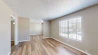 This single-floor, 2-bedroom, 1-bathroom unit offers a practical and cohesive layout designed to maximize its available space. Throughout the unit, wood-look plank flooring and neutral taupe walls create a consistent, clean aesthetic, while textured ceilings add subtle architectural character.

The living room is an open, well-lit space featuring a ceiling fan and a large window fitted with horizontal blinds, allowing ample natural light. An adjacent dining area connects seamlessly to the kitchen, which is outfitted with white cabinetry, speckled blue-grey countertops, a stainless steel refrigerator, and a dishwasher—providing efficient storage and workspace.

The primary bedroom is a generously sized room with a ceiling fan, and benefits from direct access to a walk-in closet lined with built-in shelving and dual hanging rods on both sides, offering substantial storage capacity. The second bedroom also features a large window with outdoor views and wood-look flooring. The bathroom includes a full tiled tub-shower combination, a white vanity with a stone-look countertop, and wood-look flooring. A hallway connects the rooms, completing the efficient floor plan.