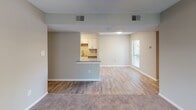 This single-floor residence offers a thoughtfully designed open-concept layout that seamlessly connects the living, dining, and kitchen areas. The living space features a combination of light wood-style vinyl flooring and plush carpeting, with a ceiling fan providing added comfort. A fireplace anchors one end of the living area, while a large window allows natural light to fill the room.

The kitchen is a standout feature, outfitted with crisp white shaker-style cabinetry, granite-look countertops, and a full suite of stainless steel appliances including a refrigerator, electric range, microwave, and dishwasher. A peninsula counter separates the kitchen from the living area, providing additional workspace and a casual dining option. The kitchen benefits from its own dedicated lighting and opens conveniently toward a utility area.

The bedroom is generously sized, finished with soft carpet, vertical blinds over a large window, a ceiling fan with light fixture, and direct access to a walk-in closet. The bathroom features white cabinetry, a clean white sink with modern fixtures, and a wall-mounted mirror. A dedicated in-unit laundry room houses a full-size washer and dryer set with overhead wire shelving for storage. The textured ceilings and neutral-toned walls throughout lend the space a clean, move-in-ready aesthetic.