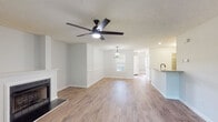 Located at 505 Regency Dr in Fayetteville, NC, this single-story home offers a thoughtfully designed layout with a blend of modern updates and comfortable living spaces. The open-concept living and dining area is anchored by a classic white fireplace and finished with warm hardwood-style flooring that flows throughout the main living spaces. A stylish black ceiling fan and an elegant geometric chandelier provide both function and character to the area. A half-wall kitchen bar with granite-style countertops connects the kitchen to the main living space, creating an easy flow for entertaining. The kitchen is equipped with light wood cabinetry, granite-style countertops, and black appliances, including an electric range and built-in microwave. The bedrooms feature plush carpeting, ceiling fans, and ample natural light from windows dressed with blinds. Each bedroom includes closet space, with the primary bedroom offering a walk-in closet. The primary bathroom is well-appointed with a single vanity with granite-style counters, a soaking tub, and wood-style flooring. A secondary bathroom provides a full tub-shower combo and matching vanity finishes. Neutral gray walls and textured ceilings are consistent throughout, creating a clean, cohesive aesthetic.