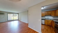 Located in Eden Prairie, MN, this 2-bedroom, 2-bathroom single-floor residence offers a practical and comfortable layout. The living room serves as the heart of the home, featuring warm hardwood-style flooring, a textured ceiling, and a sliding glass door that fills the space with natural light while offering views of the lush, tree-lined grounds outside. A wall-mounted AC unit provides climate control directly in the living area.

The kitchen is efficiently designed with warm wood cabinetry, granite-style countertops, and stainless steel appliances including a refrigerator and dishwasher. It connects seamlessly to the living area, supporting an open and functional flow.

Both bedrooms are carpeted for comfort and include sliding-door closets with built-in shelving. Natural light enters through blinded windows, and baseboard heating ensures warmth throughout the cooler months. The space includes a generous five closets in total, providing abundant storage options.

The bathrooms feature tile flooring, wood-toned vanities with white countertops, and a tub-shower combination. The surrounding outdoor area showcases a wide open lawn with mature trees, offering a serene natural backdrop visible from within the home.