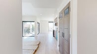 Located at 154 S Occidental Blvd in Los Angeles, this modern 2-bedroom, 3-bathroom unit offers a thoughtfully designed open-concept layout with clean, contemporary finishes. Light wood-style flooring runs throughout the entire space, creating a cohesive and airy feel. The combined kitchen and living area serves as the heart of the unit, featuring flat-panel warm wood cabinetry, white quartz countertops, a subway tile backsplash, and a full suite of stainless steel appliances including a range, microwave, refrigerator, and a distinctive turquoise dishwasher. Large sliding glass doors and floor-to-ceiling windows flood the living area with natural light and provide views of the surrounding neighborhood. The two bedrooms are well-proportioned, each featuring large windows with roller shades, recessed lighting, and light-filled interiors. Stylish flat-panel wood interior doors with matte black hardware add a refined touch throughout. The three bathrooms showcase walk-in showers tiled in a herringbone pattern, mosaic tile flooring, and chrome fixtures, offering a clean and modern aesthetic. The overall ambiance of the space is bright, minimalist, and move-in ready, reflecting a fresh, contemporary design sensibility well-suited for urban Los Angeles living.