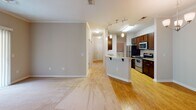 Located at 7104 Moonseed Ln in Southern Pines, NC, this single-floor home offers a well-designed, functional layout with a cohesive blend of hardwood and carpeted flooring throughout. The open-concept kitchen is a central highlight, featuring rich dark cabinetry, granite countertops, stainless steel appliances including a gas range, microwave, and refrigerator, and a peninsula with bar seating that connects seamlessly to the living and dining areas. Track lighting and pendant fixtures add a modern touch overhead, while crown molding lends a refined finish to the main living space. The living area is generously sized, equipped with a ceiling fan, and opens to the outdoors through sliding glass doors with vertical blinds, allowing for natural light and exterior access. Multiple carpeted bedrooms are bright and well-proportioned, each featuring windows that bring in natural light and views of the surrounding greenery. The bathrooms are outfitted with dark wood vanities, granite countertops, large mirrors with Hollywood-style lighting, and tile flooring. One bathroom includes a full tub-shower combination, while another serves as a convenient half bath. The hallways are clean and well-lit, connecting the spaces with a practical, flowing layout.