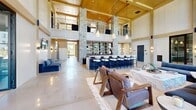 Located at 80 Batterson Park Rd in Farmington, CT, this impressive single-floor clubhouse offers a thoughtfully designed layout spanning a generous footprint. The grand entrance lobby immediately sets the tone with soaring double-height ceilings, exposed wood beam accents, polished concrete floors, and floor-to-ceiling black-framed windows that flood the space with natural light and offer views of the surrounding landscape.

The expansive living area serves as the heart of the space, anchored by a striking stacked-stone fireplace beneath a warm wood-paneled cathedral ceiling. An upper mezzanine overlooks the room, adding architectural depth, while a full bar with built-in shelving and counter seating provides an ideal gathering spot. Stylish pendant lighting and carefully curated furnishings contribute to the space's sophisticated yet comfortable ambiance.

The dining room features herringbone hardwood flooring, rich olive-toned walls, a solid wood farmhouse table, and an elegant gold-accented chandelier, with sliding glass doors opening to an outdoor patio. A cozy secondary lounge boasts built-in wood shelving, teal-hued walls, leather furnishings, and a large picture window with outdoor views. The kitchen is outfitted with warm wood cabinetry, white countertops, and stainless steel double wall ovens, offering full functionality for events and gatherings.