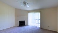 Located at 310 Abbey Ct in Biloxi, Mississippi, this single-story home offers a comfortable and functional layout designed for easy living. The living area serves as the heart of the space, highlighted by a classic fireplace with a brick hearth and a clean white mantle, providing a warm focal point for the room. Plush wall-to-wall carpeting adds comfort underfoot, while a ceiling fan with a light fixture ensures year-round comfort and air circulation. A full-height sliding glass door dressed with vertical blinds floods the room with natural light and provides seamless access to the outdoor area, creating a bright and airy atmosphere. The textured ceiling and neutral wall tones throughout give the space a clean, understated aesthetic that is easy to personalize. The single-floor design offers convenient, step-free living throughout, making it an accessible and practical choice. The home's location in Biloxi, MS places it within reach of the Gulf Coast's amenities, combining everyday comfort with a desirable coastal setting.