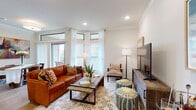 This single-floor residence offers a thoughtfully designed layout that balances comfort and functionality across its key living areas. The living room serves as the heart of the home, featuring crown molding, recessed lighting, and an abundance of natural light streaming through large corner windows dressed with sheer white curtains. A sliding glass door provides access to an outdoor area, further enhancing the bright, airy atmosphere.

The kitchen is well-equipped with white cabinetry, granite countertops, stainless steel appliances including a French door refrigerator and electric range, and light wood-tone flooring. A peninsula with bar seating adds both prep space and casual dining convenience. Pendant lighting overhead adds a polished finishing touch. Adjacent to the kitchen, a dining area accommodates a round wood table beneath a bold abstract artwork, with a sliding panel door allowing for natural light.

The bedrooms feature plush carpeting, crown molding, ceiling fans, and ample natural light from well-positioned windows with blinds. Walk-in closets provide generous storage. The bathroom is finished with marble-style subway tile surrounding a soaking tub and shower combination, complemented by wood-look flooring and warm neutral tones throughout, creating a clean, spa-inspired retreat.