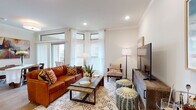 This single-floor residence offers a thoughtfully designed layout that balances comfort and functionality across its key living areas. The living room serves as the heart of the home, featuring crown molding, recessed lighting, and an abundance of natural light streaming through large corner windows dressed with sheer white curtains. A sliding glass door provides access to an outdoor area, further enhancing the bright, airy atmosphere.

The kitchen is well-equipped with white cabinetry, granite countertops, stainless steel appliances including a French door refrigerator and electric range, and light wood-tone flooring. A peninsula with bar seating adds both prep space and casual dining convenience. Pendant lighting overhead adds a polished finishing touch. Adjacent to the kitchen, a dining area accommodates a round wood table beneath a bold abstract artwork, with a sliding panel door allowing for natural light.

The bedrooms feature plush carpeting, crown molding, ceiling fans, and ample natural light from well-positioned windows with blinds. Walk-in closets provide generous storage. The bathroom is finished with marble-style subway tile surrounding a soaking tub and shower combination, complemented by wood-look flooring and warm neutral tones throughout, creating a clean, spa-inspired retreat.