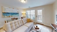This thoughtfully designed 2-bedroom, 2-bathroom residence offers a cohesive blend of modern finishes and comfortable living across a single floor. The open-concept layout connects the kitchen and living areas seamlessly, creating a welcoming, functional space. The kitchen is equipped with stainless steel appliances, white shaker-style cabinetry, light quartz countertops, a classic subway tile backsplash, and a peninsula with pendant lighting and bar seating — ideal for casual dining and entertaining. The adjacent living area is bright and airy, featuring warm wood-look flooring, neutral walls, and a glass-paneled door leading to a private balcony with outdoor views. The primary bedroom is generously sized, bathed in natural light from a large window, and connects to an en-suite bathroom with a walk-in glass shower, white vanity cabinetry, and a vessel sink. The second bedroom is equally comfortable, offering closet storage and easy access to the second full bathroom, which features a combined tub and shower, a white vanity, and warm-toned walls. Wood-look flooring flows consistently throughout the entire residence, tying each space together with a clean, contemporary aesthetic.