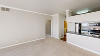 Located at 2 Enterprise in Aliso Viejo, CA, this well-appointed single-floor residence offers a thoughtfully designed layout with a clean, neutral aesthetic throughout. The living room is a welcoming centerpiece, featuring plush carpeting, crown molding, a ceiling fan, a classic fireplace with a white mantel, and a large window with vertical blinds that invite abundant natural light. Adjacent to the living area, the kitchen is outfitted with crisp white cabinetry, dark countertops, and stainless steel appliances including a range, over-the-range microwave, and refrigerator, complemented by wood-look flooring. A dedicated laundry area provides the convenience of an in-unit washer and dryer. The bedrooms are generously sized, each with soft carpeting and ceiling fans, and include walk-in or reach-in closets with built-in shelving for ample storage. The bathroom features a tub-shower combination, wood-look tile flooring, white cabinetry with a dark countertop vanity, pendant lighting, and open built-in shelving. An outdoor balcony with textured stucco walls and a railing offers a private outdoor retreat with views of surrounding greenery, completing this comfortable and functional Aliso Viejo residence.