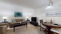 Located at 9056 W Waterford Square S in Greenfield, Wisconsin, this single-floor residence offers a thoughtfully arranged layout designed for comfortable everyday living. The open living and dining area is carpeted throughout and filled with natural light from a large sliding glass door that opens to an outdoor view, creating a bright and welcoming atmosphere. The space flows naturally between a seating area and a dining nook, making it ideal for both relaxing and entertaining.

The kitchen features warm oak cabinetry with ample upper and lower storage, white countertops, a double-basin sink, and tile flooring. A laundry area is conveniently accessible directly from the kitchen, adding practical functionality to the space.

The bedroom is generously sized, featuring soft carpet, a teal accent wall, and a wide sliding-door closet that provides substantial storage. A cozy sitting nook within the bedroom offers a quiet retreat, complete with natural light from a large window.

The bathroom is clean and functional, featuring a full vanity with oak cabinetry, a framed mirror, and a tiled tub-shower combination equipped with a safety grab bar. The overall design of this residence combines practical features with a warm, comfortable ambiance suited for single-level living.